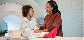 Parent reassuring child on table in front of scanner.