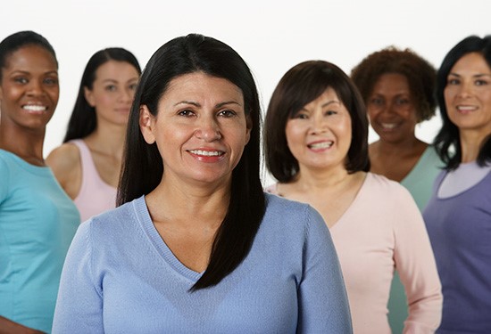 Group of women of different ethnicities and sizes standing together and smiling at the camera