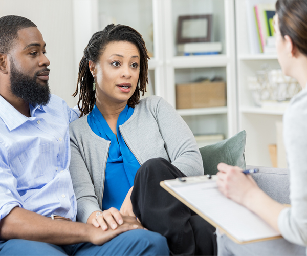 Image of an African American couple speaking to a healthcare provider, who is holding a clipboard