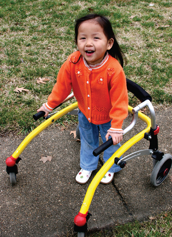 Young girl with cerebral palsy using a walker to move independently.