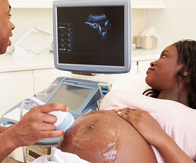 Medical professional performing ultrasound on pregnant woman in a doctor's office.