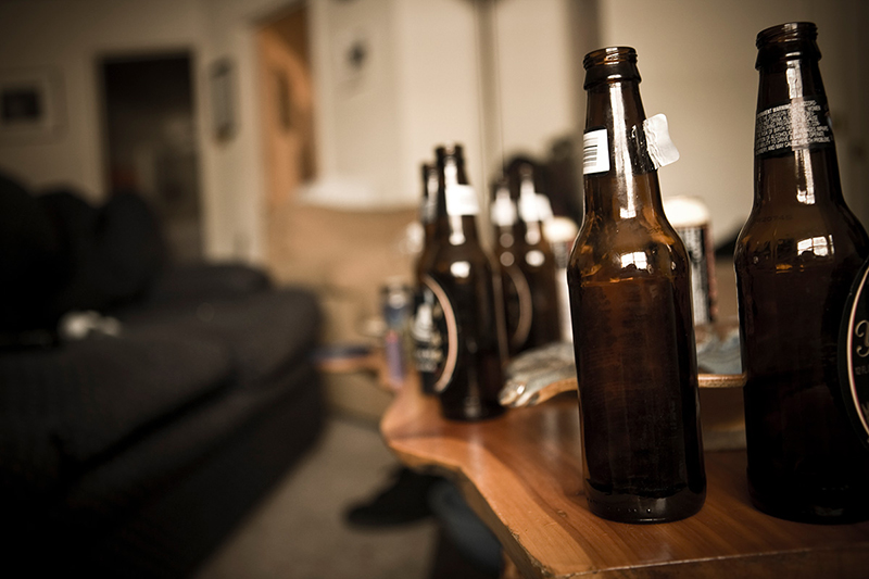 Multiple empty beer bottles on a coffee table.