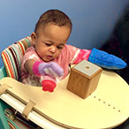 A toddler in a high chair, playing with toys.