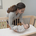 Person putting a baby on their back to sleep.