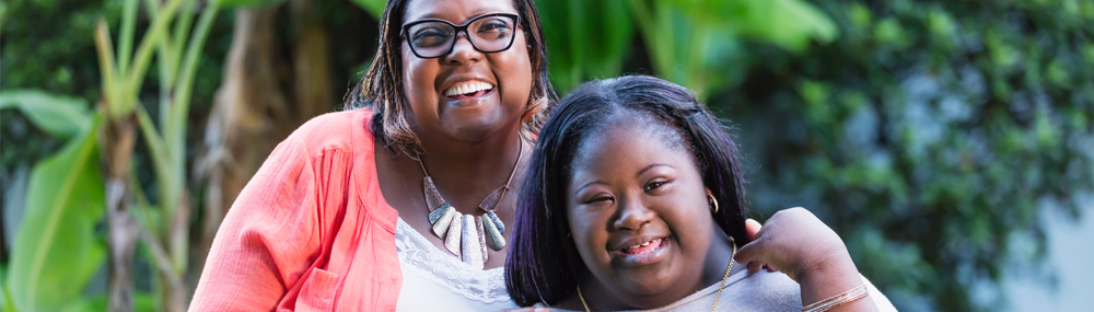 A young woman with Down syndrome and her grandmother. Both are smiling. 