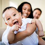 Parents holding smiling baby.