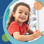 Photo of young child smiling and writing with a pencil with circles surrounding the image.