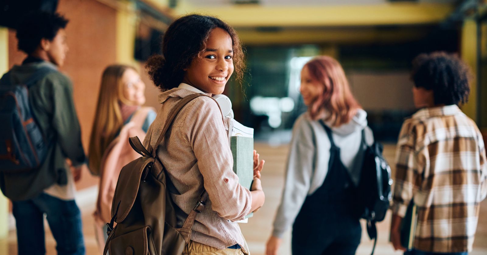 Teenagers with backpacks in a school hallway.