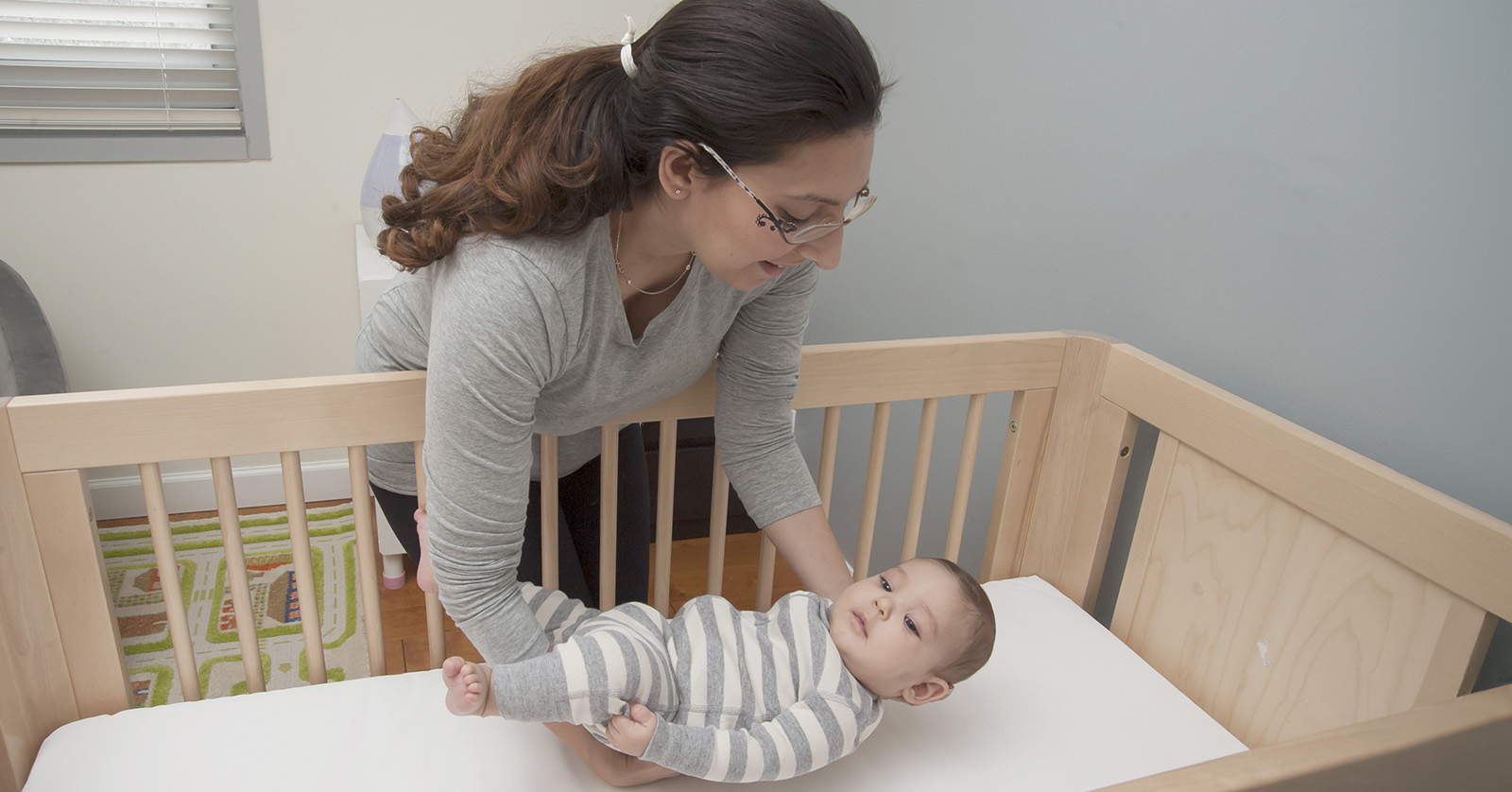 Person putting a baby on their back to sleep.