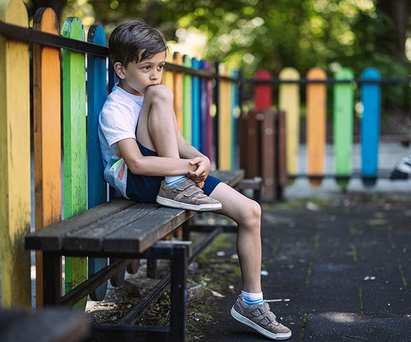 Child sitting alone on a playground bench. 