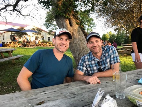 Twins sitting at a picnic table.