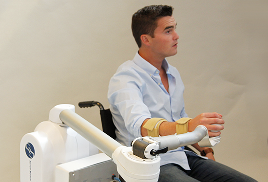 A man uses a robotic arm for  rehabilitation therapy. Credit: William Townsend, Barrett Technology